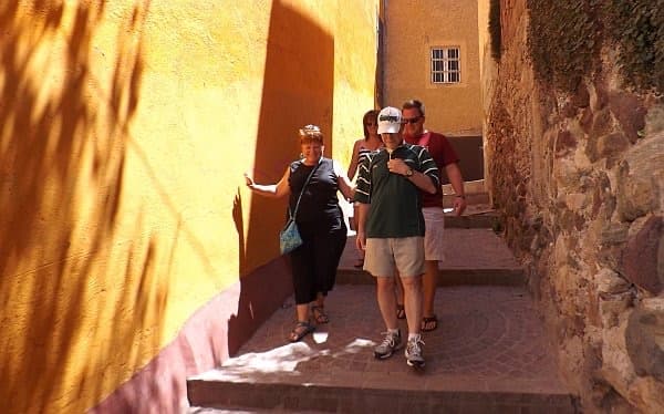 Guests walking down a stepped, sunlit ochre alley